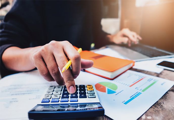 An accountant working through figures on a calculator and printed reports